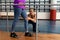 Female physiotherapist helping disabled senior woman walk with parallel bars in sports center