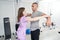 Female physiotherapist helping man to perform rehabilitation exercise