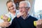 Female Physiotherapist Helping Senior Man To Lift Hand Weights At Home