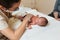 Female physiotherapist wearing a face mask while examining a newborn baby in a medical center.