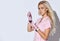 Female in pink scrubs and disposable gloves is posing isolated on white. Holding brush, glass bowl with black liquid. Close up