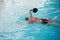 Female in pink swimwear swimming in blue water pool with special equipment.