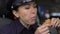 Female police officer having breakfast, eating cheeseburger sitting in car