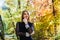 Female porteait in autumn park. Beaurtiful woman in black dress posing with yellow trees