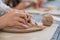 Female potters hand making clay pottery at the table with a different wooden tools close up.