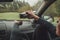 Female pouring the hot tea in tourist thermos mug. She sitting on co-driver seat inside modern car, enjoying the moody rainy day