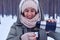 Female pouring tea from thermos to the cup in a snowy forest