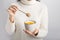 Female preparing turmeric latte drink with honey on gray