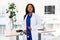 Female pretty African doctor in white coat looking to camera in an modern medical office