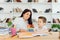 Female private tutor helping young student with homework at desk in bright child`s room