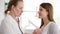 Female professional doctor at work. Woman physician using stethoscope for listening patient`s lungs