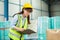 Female professional worker holding folder checking stock product in warehouse logistic storage. woman employee checklist package