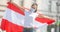 Female in protective mask holds a flag of Austria behind her outdoors on a sunny day