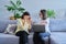 Female psychologist and middle aged woman patient sitting together on couch in office