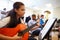 Female Pupil Playing Guitar In High School Orchestra