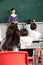 Female Pupil Writing On Blackboard In School