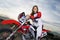 Female Racer Sitting On Motorcycle Against Cloudy Sky