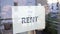 Female real estate agent hangs a FOR RENT sign on window of apartment.