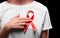 A female with a red ribbon on a white T-shirt on a black background. Modern treatment and healthcare. AIDS awareness