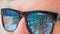 Female reflection in mirrored sunglasses close up. Flirting playful woman in bikini sending air kiss to man in mirrored