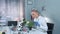 Female research scientist in protective glasses examining plant leaves with tweezers