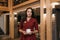A female restaurant manager in a ruby dress is holding a cup of coffee