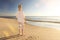 Female retiree standing at the beach and looking towards the ocean with lens flare