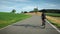 Female road cyclist riding on bicycle up an asphalt road in sunshine. Woman cycling on road bike through fields and meadow at suns