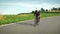 Female road cyclist riding on nice asphalt road surrounded by fields and meadows at sunset. Woman cycling outdoors in evening suns