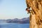 Female rock climber on challenging route on cliff, view of coast