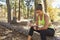 Female runner in a forest sits checking her smartwatch