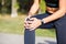 Female runner holding aching knee at jogging