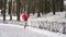 Female runner jogging in cold winter forest wearing warm sporty running clothing and gloves.