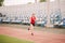 Female runner jogging on stadium track, woman athlete running and working out outdoors, sport and fitness concept. Young woman in