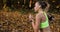 Female runner in the park. Woman in colorful jogging suit listens to the music and runs along the path in the park