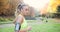 Female runner in the park. Woman in colorful jogging suit listens to the music and runs along the path in the park