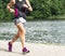 Female runner racing 10K on a trail around a lake