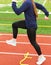 Female runner stepping over yellow mini hurdle on a track