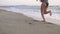 Female running, jogging barefoot on ocean beach sand at sunrise