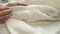 Female\'s hand on the fabric of white plush cloth with soft nap. clothing industry concept, slow motion. Woman