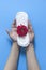 Female`s hand holding sanitary napkins with red rose on it. Period days concept showing feminine menstrual cycle. Female`s hygie