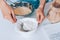 Female`s hands scoop flour in sieve to sift it into the dough