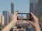 Female`s hands take a picture of Dubai monorail and skyscrapers on mobile phone. Picture of subway road on downtown city Dubai