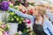 Female sales assistant working as florist and holding bouquet with customer in background. Horizontal shape, waist up.