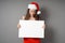 Female santa looking down at blank sign with copy space