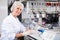 Female scientist engaged in research in chemical laboratory noting results in chart