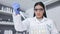 Female scientist experimenting with test tubes and a syringe. One young biologist or chemist putting blue liquid in