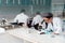 Female scientist in eyeglasses working with microscope while colleagues sitting behind in lab