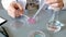 Female scientist hands pouring liquid from pipette over pink glitter sample on a petri dish in lab