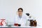 Female scientist holding her glasses and looking with both test tubes and writes experimental summary on clipboard while